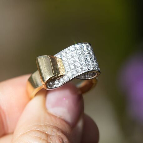 Geelgouden strik ring volop bezet met briljant